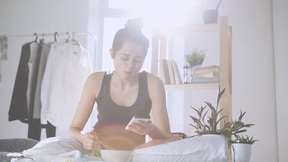 Caucasian Girl Eating Breakfast and Checking News in Smartphone in Slowmotion