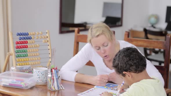 boy child doing homework learning at home with mother sitting at a table stock video