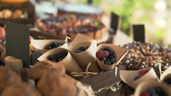 Berries Lie in Paper Bags in a Wooden Box on a Table with Pies Outdoors