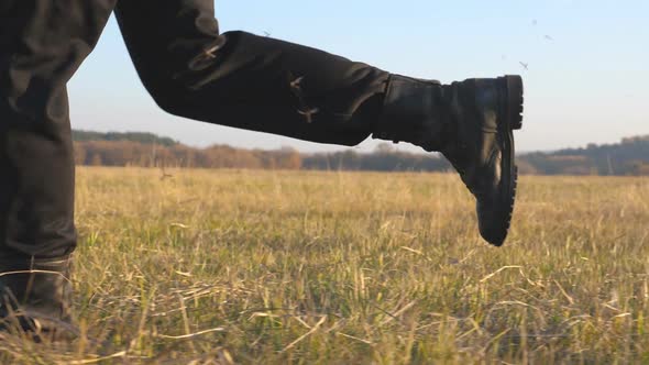 Feet of Soldier in Black Boots Run Across Field and Stepping on Dry Grass