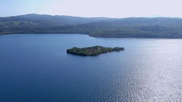 small wooded island in the middle of the thermal power plant lake with forests behind the horizon an