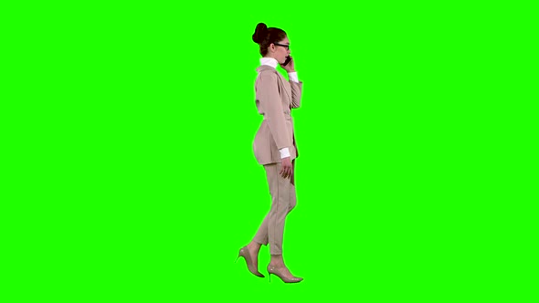 Businesswoman Is Walking and Talking on the Phone. Green Screen. Side View. Slow Motion