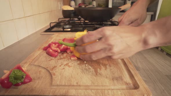 Red And Yellow Capsicum Chopped In Wooden Board In Kitchen's Countertop. Closeup