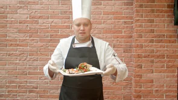 Friendly Chef in Uniform Present a Plate with Seafood Salad, Talking To a Camera