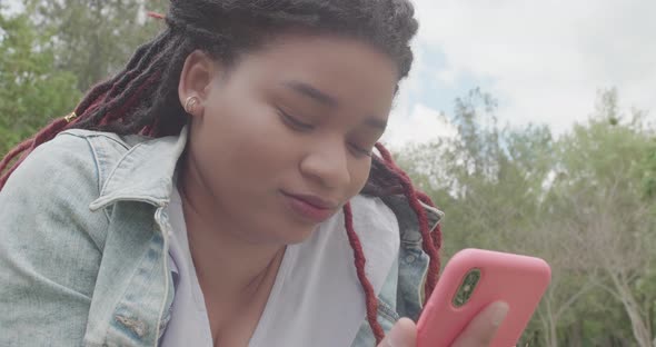 Close Up Portrait of Afro Woman Using Smartphone and Smiling on Nature Background