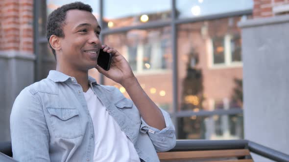 African Man Talking on Phone Sitting Outdoor