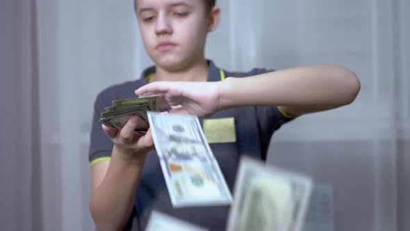 Successful Teenager Scatters a Lot of 100Dollar Bills While Sitting in a Chair