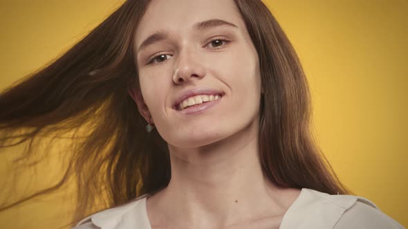 Young Adult Caucasian Woman is Posing on a Bright Yellow Background in Studio