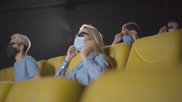 People Watching Movie in Cinema on Coronavirus Pandemic. Angle View of Men and Women in Face Masks