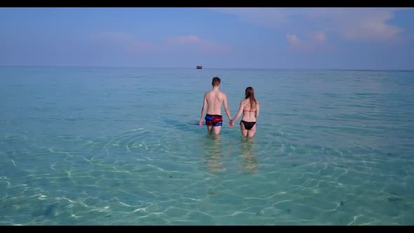 Boy and girl posing on beautiful resort beach lifestyle by aqua blue water and white sandy backgroun