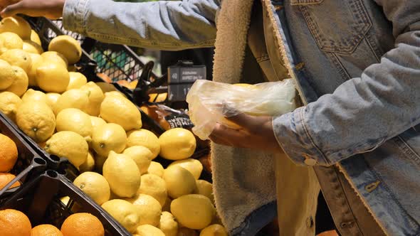 African American Guy Puts Yellow Lemons Into Plastic Bag