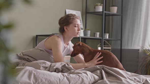 Pretty Young Woman Playing with Pet in Bed