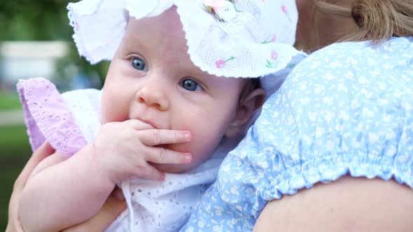 Baby Girl with Blue Eyes Looks Around Sitting in Mother Arms