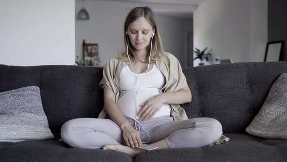 Tranquil Pregnant Woman Listening To Music From Smartphone