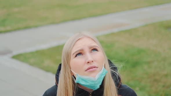 Young Female Looking Into the Sky and Putting on Medical Mask