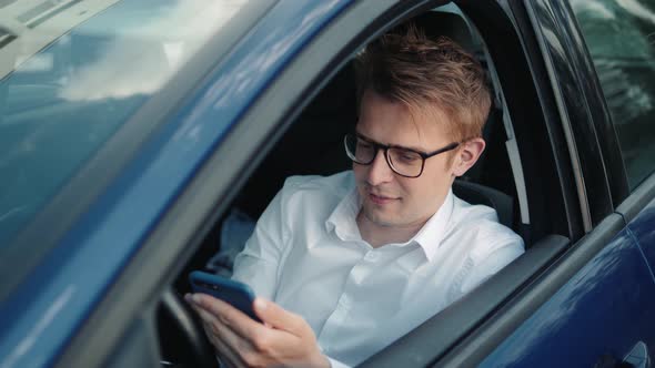 Happy Man Sitting Inside Car Using a Smart Phone Voice Recognition Function on Line Outdoors on a