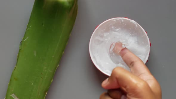 Fresh Aloe Vera Sliced and Liquid Gel in Plastic Container on White Background