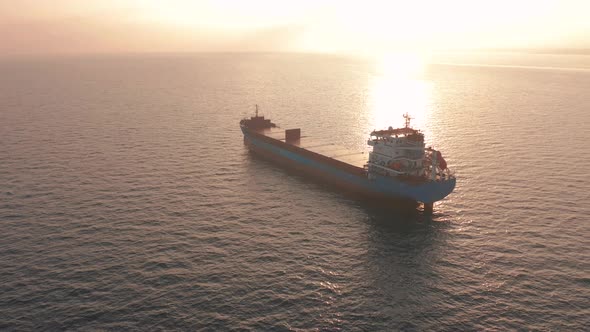 Aerial View. Beatiful Sunset at the Sea. Huge Cargo Ship Floating in the Sea