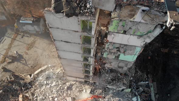 An Excavator Tractor Digs the Concrete Ruins of a Collapsed House with a Bucket