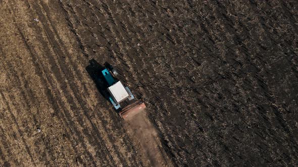 Aerial View of Agricultural Tractor Preparing Land Harrows the Soil on the Fertile Farm Fields