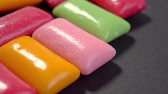 Multicolored chewing gum pads on a black background close-up. Colourful chew candy. Macro