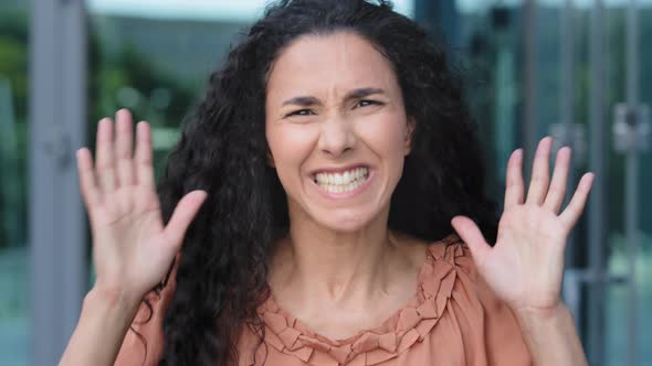 Female Portrait of Young Hispanic Woman with Curly Long Hair Stands Outdoors Shouts Angry Waving