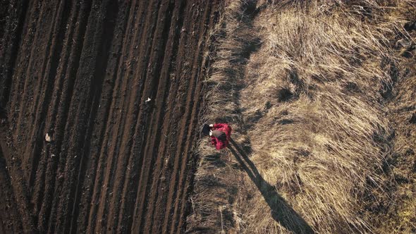 Aerial View of Woman Farmer with Digital Tablet Computer Looks at a Fresh Plowed Field After Winter