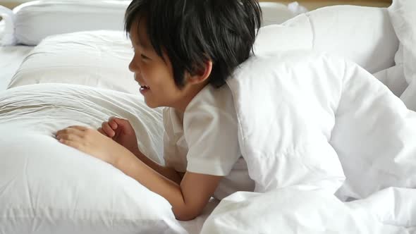 Cute Asian Child Playing Hide And Seek On White Bed
