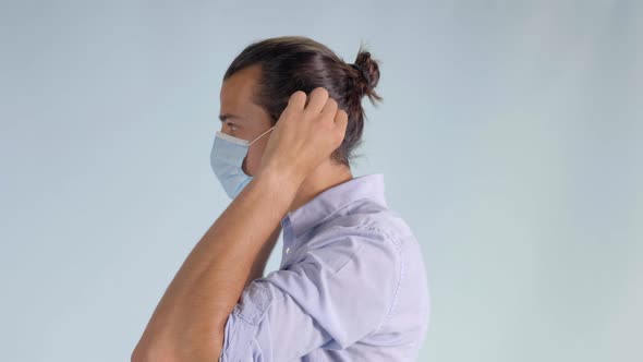 Demonstration of Young Man Putting on Protective Face Mask, Closeup Profile