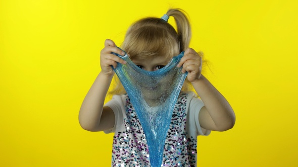 Kid Playing with Hand Made Toy Slime. Child Having Fun Making Turquoise Slime. Yellow Background