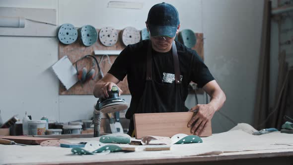 Man Worker Grinding a Wooden Pieces Using an Instrument