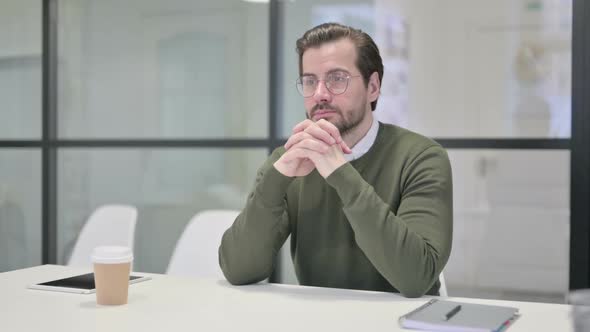 Pensive Young Businessman Thinking While Sitting in Office