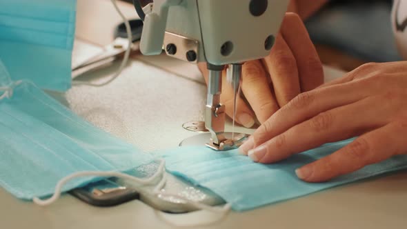 Woman hands using the sewing machine to sew the face medical mask