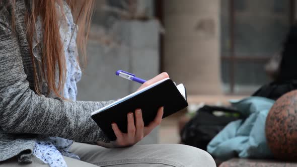 Hand of Young Woman Student Making Notes in Notebook