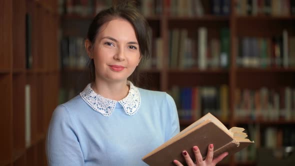 Portrait of Smiling Beautiful Pretty Woman with Book in Library Office Bookshelf Background