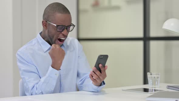 African Man Celebrating While Using Smartphone