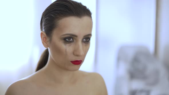 Woman with Smeared Mascara Looks at the Mirror