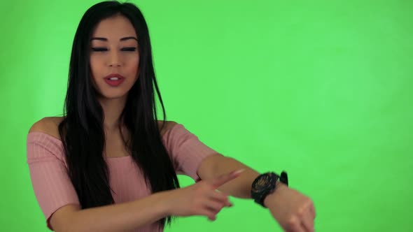 Young Attractive Asian Woman Points To Watch - Green Screen Studio