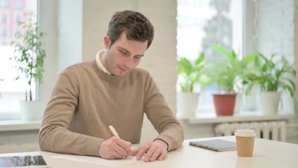 Man Writing on Paper in Office