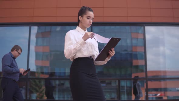 A Business Woman is Looking at Working Papers While a Businessman and a Business Woman are Taking