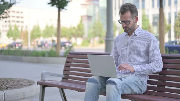 Young Adult Man Leaving Bench After Closing Laptop