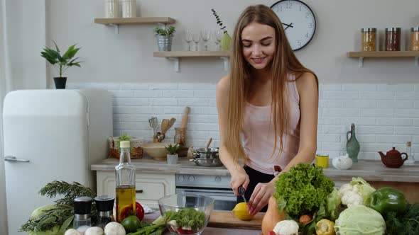 Girl Coming To Table with Juicy Lemon. Young Woman Cutting Fresh Fruit with Knife and Smiling