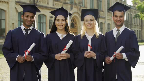 International students in graduation outfit holding diplomas, quality education