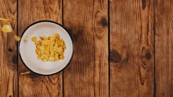 Cornflakes Falling in the Bowl on Wooden Table, Slow Motion. Top View