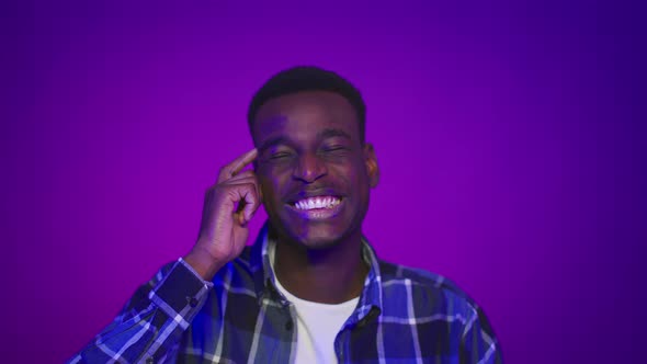 Toothy African Man Pointing Finger At His Head Purple Background