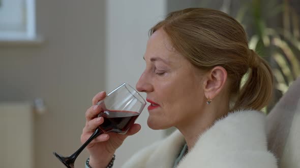 Closeup of Confident Middle Aged Elegant Woman Drinking Wine From Glass Sitting at Home Indoors