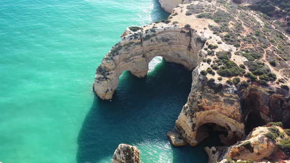 Ocean eroded rock arch formations in Marinha Beach south of Portugal, Aerial approach shot