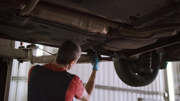 Auto Mechanic Repairs Car on the Lift in the Service Station