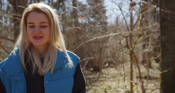 blonde girl laughs then straightens her hair in the forest at sunset