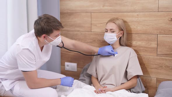 Young Male Doctor Is Listening To Breath of Male Patient